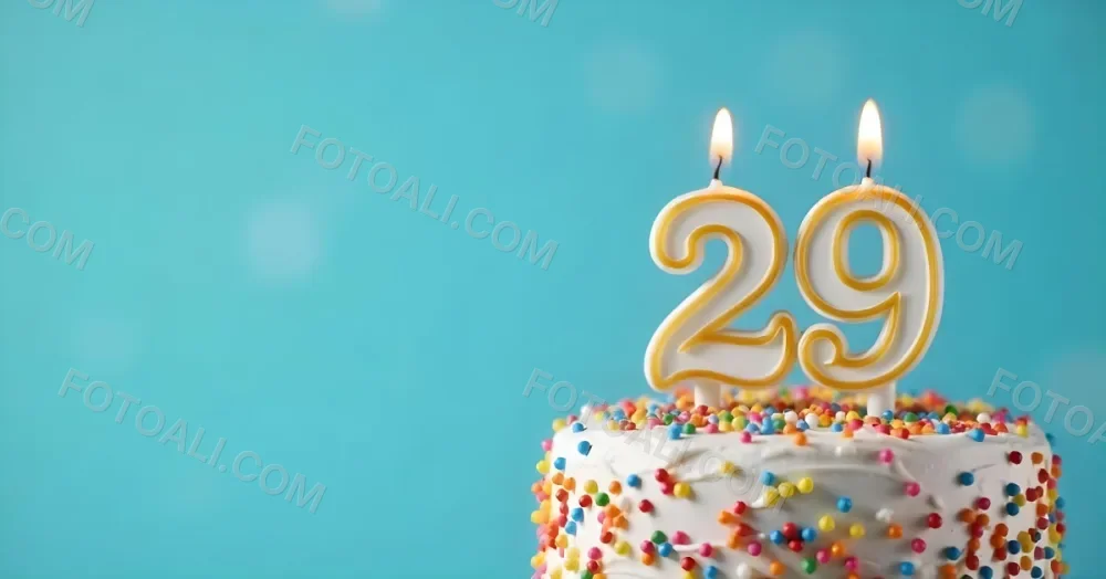 A Cake With White Frosting And Colorful Sprinkles Topped With A Candle In The Shape Of The Number 29 Blue Background 1 3353