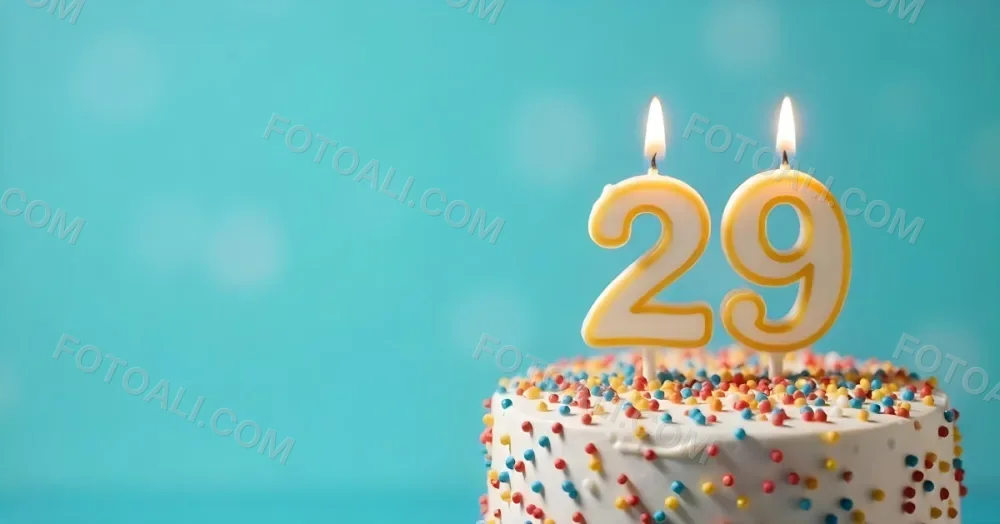 A Cake With White Frosting And Colorful Sprinkles Topped With A Candle In The Shape Of The Number 29 Blue Background 3 43d5