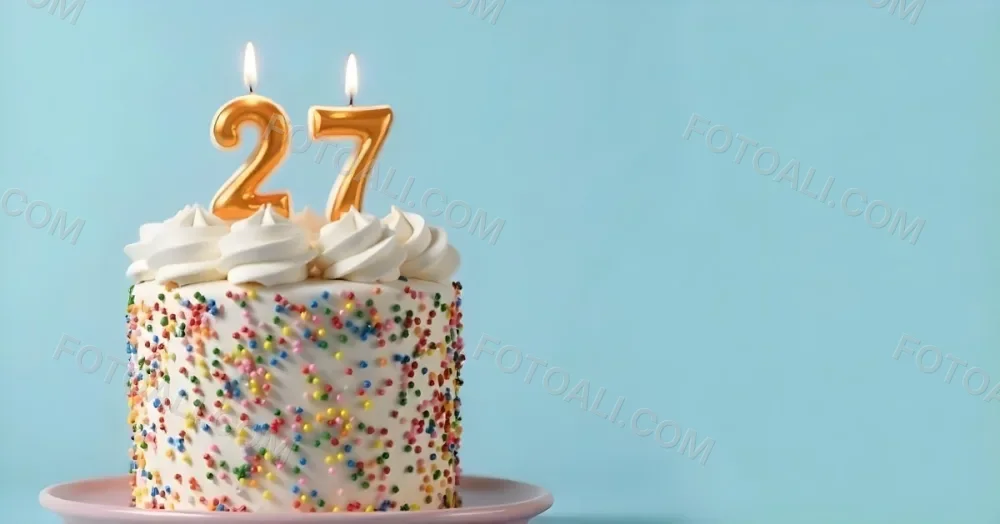 A Cake With White Frosting And Colorful Sprinkles Topped With Two Lit Candles Shaped Like The Numbers 2 And 7 On A White Plate With A Pink Background 3 D111