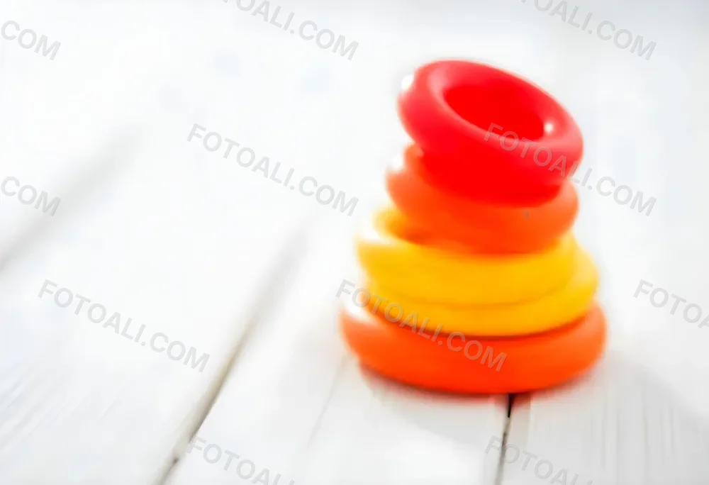 A Red Yellow And Orange Stacking Ring Toy On A White Wooden Surface The Rings Are Plastic And Shiny Close Up Shot 18 C415