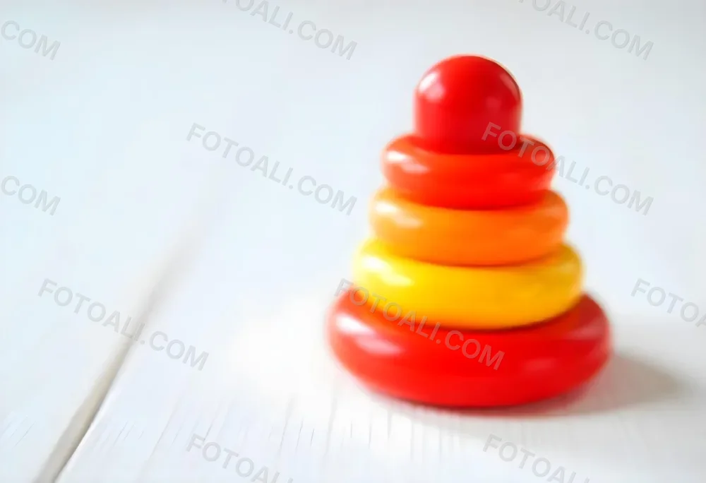 A Red Yellow And Orange Stacking Ring Toy On A White Wooden Surface The Rings Are Plastic And Shiny Close Up Shot 29 56cd