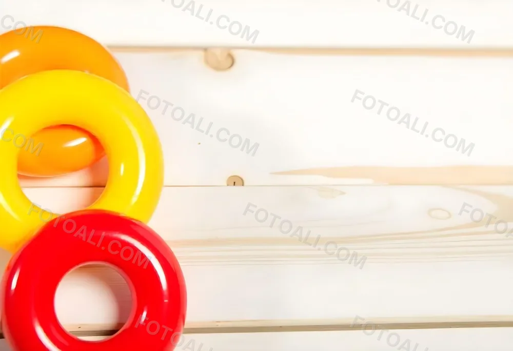A Red Yellow And Orange Stacking Ring Toy On A White Wooden Surface The Rings Are Plastic And Shiny Close Up Shot 40 175a