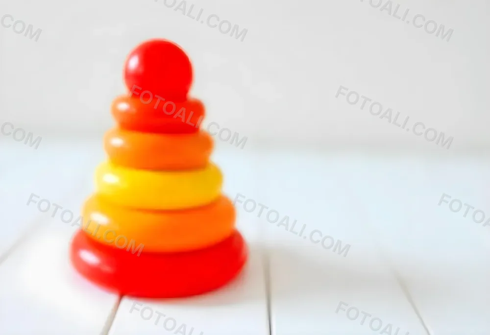 A Red Yellow And Orange Stacking Ring Toy On A White Wooden Surface The Rings Are Plastic And Shiny Close Up Shot 41 Eeb2