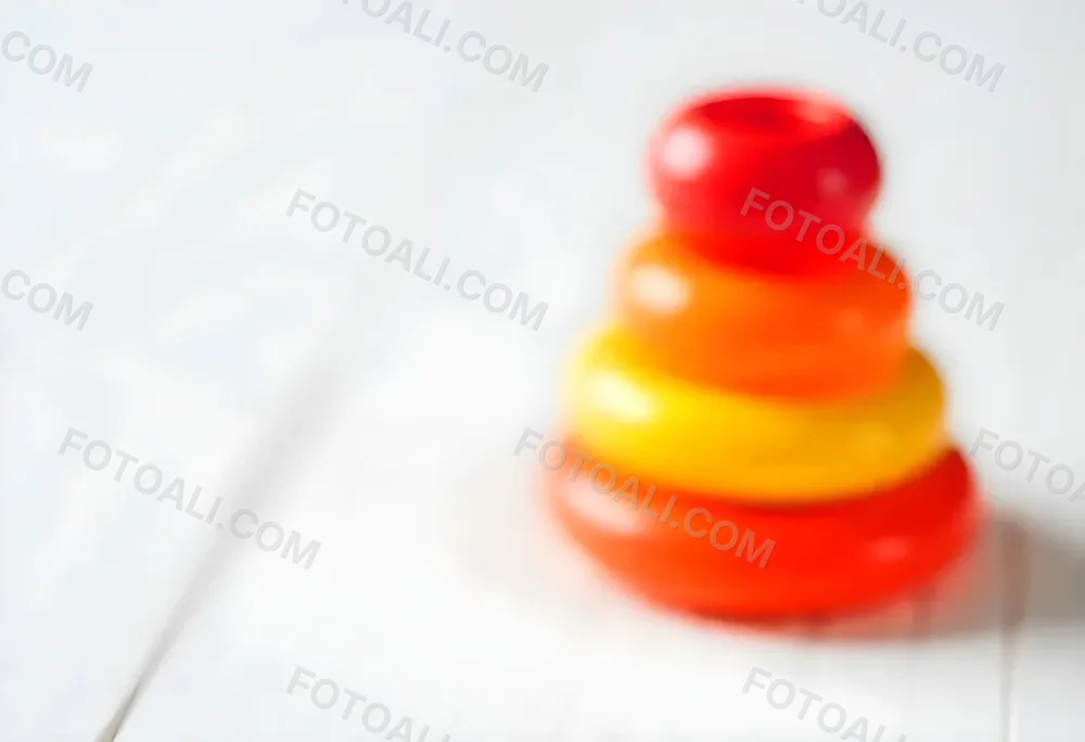 A Red Yellow And Orange Stacking Ring Toy On A White Wooden Surface The Rings Are Plastic And Shiny Close Up Shot 43 1571