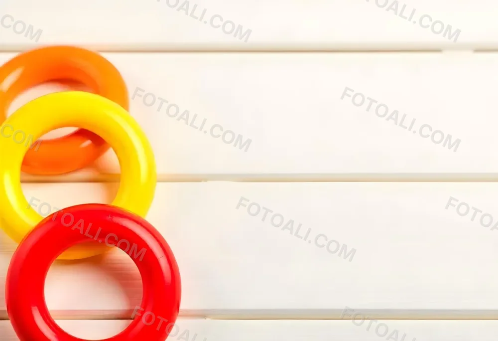 A Red Yellow And Orange Stacking Ring Toy On A White Wooden Surface The Rings Are Plastic And Shiny Close Up Shot 47 B64a