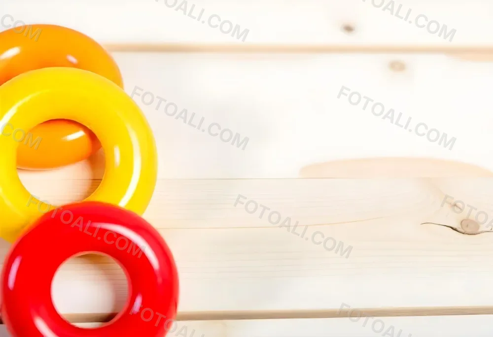 A Red Yellow And Orange Stacking Ring Toy On A White Wooden Surface The Rings Are Plastic And Shiny Close Up Shot 6 C5a1