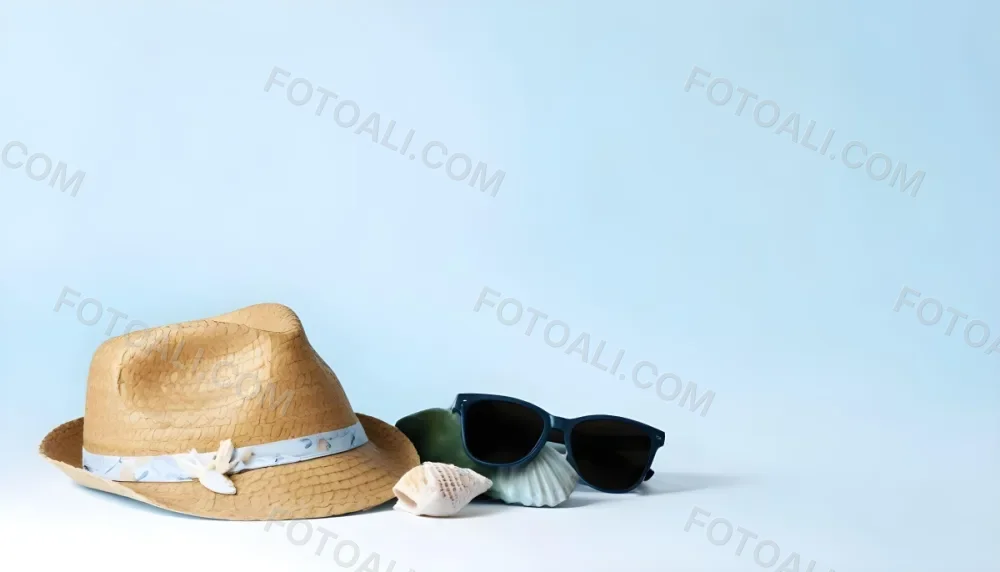 A Straw Hat With A Blue Ribbon Black Sunglasses A Seashell And A Seashell On A White Surface With A Light Blue Background 6 A21a
