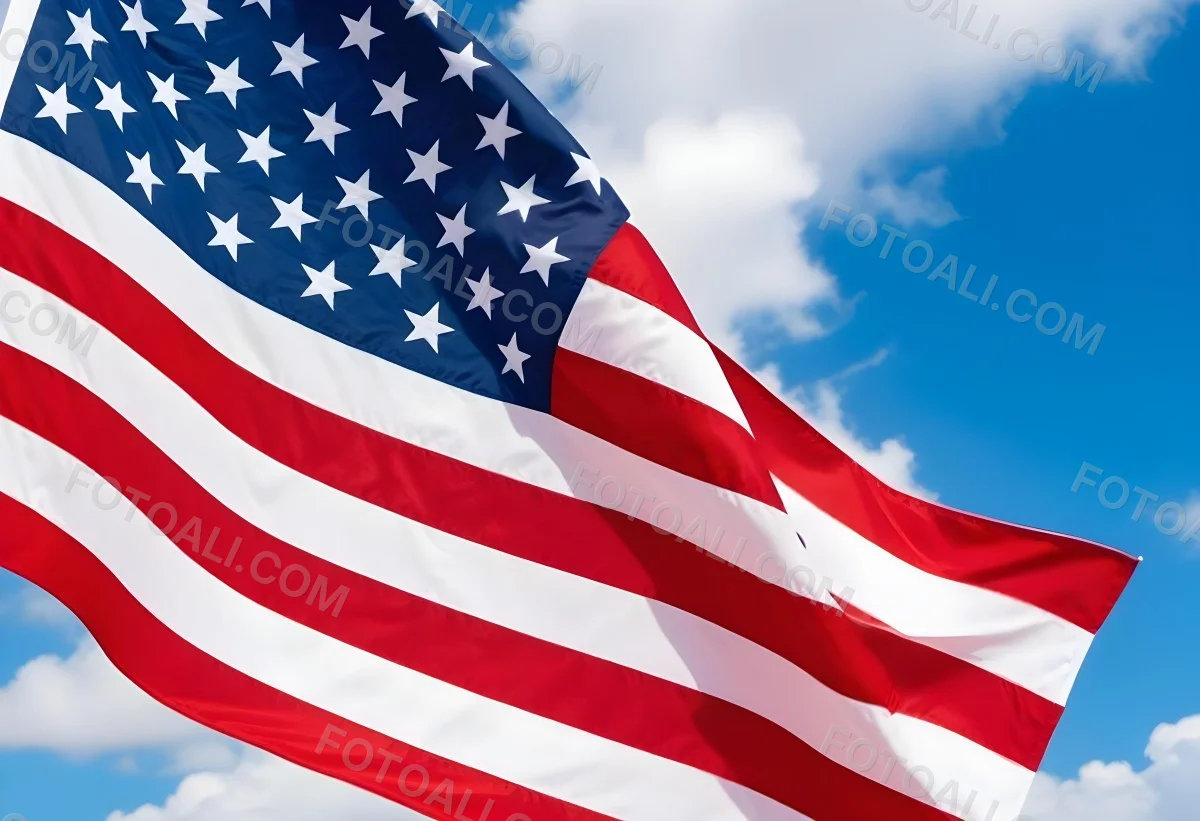 American Flag Waving In The Wind With Its Red And White Stripes And Blue Field Of Stars Against A Blue Sky With White Clouds 13 34bf