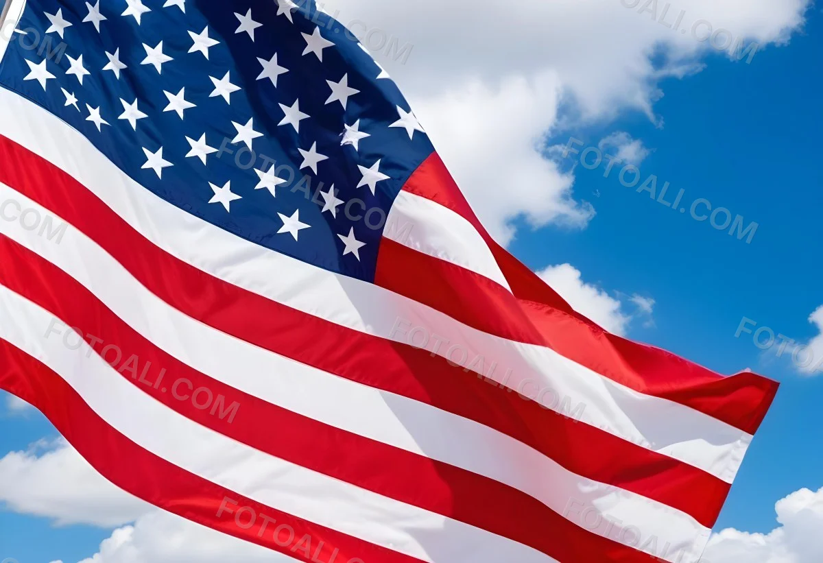 American Flag Waving In The Wind With Its Red And White Stripes And Blue Field Of Stars Against A Blue Sky With White Clouds 6 4ab2
