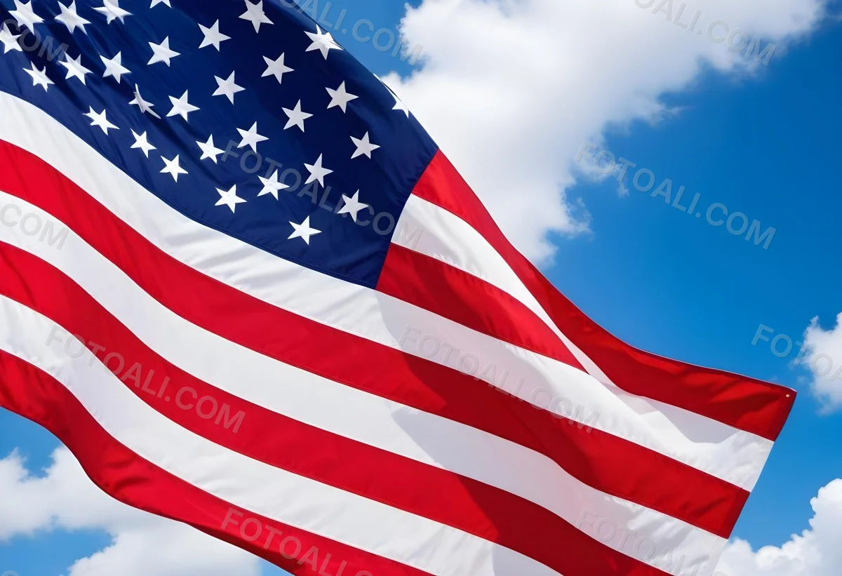 American Flag Waving In The Wind With Its Red And White Stripes And Blue Field Of Stars Against A Blue Sky With White Clouds 7 B440
