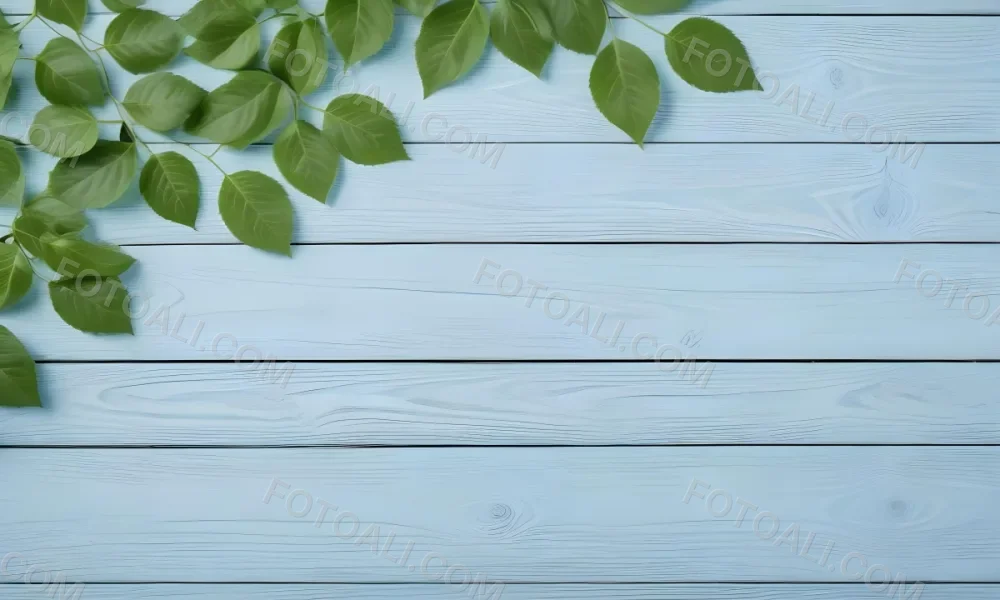 Green Leaves On A Light Blue Wooden Surface The Leaves Are Arranged In The Corners Of The Image The Background Is A Light Blue Color 4 E54a