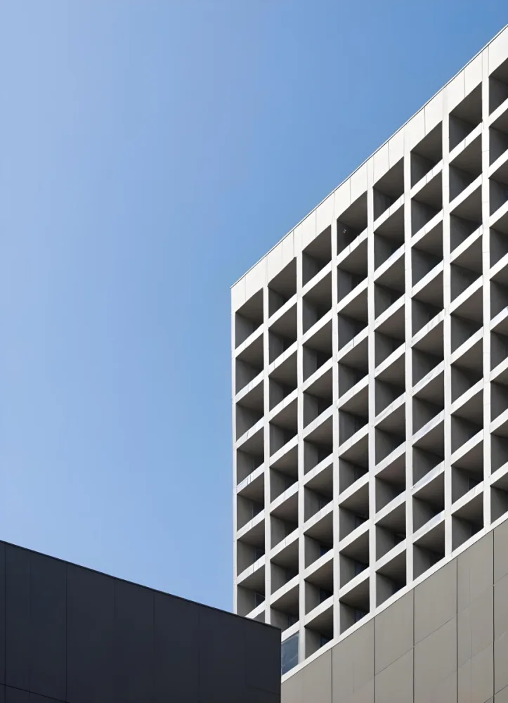 A Modern High Rise Building With A Grid Like Facade Against A Clear Blue Sky 10 8bca