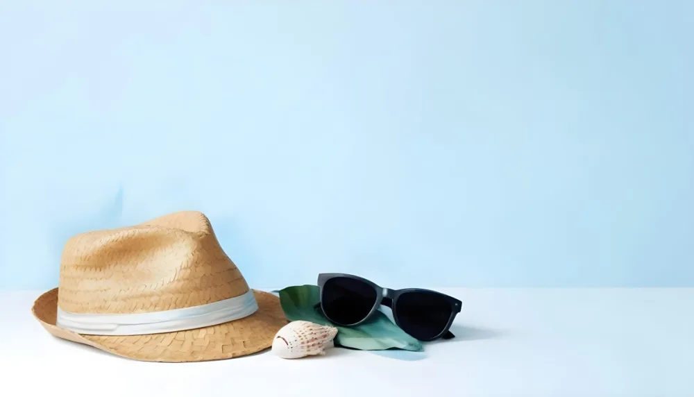 A Straw Hat With A Blue Ribbon Black Sunglasses A Seashell And A Seashell On A White Surface With A Light Blue Background 9 38d6
