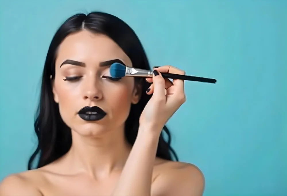 A 22 Year Old Hispanic Woman With Blue Hair Applying Makeup With A Brush Black Lipstick Closed Eyes In A Black Background 8 7622