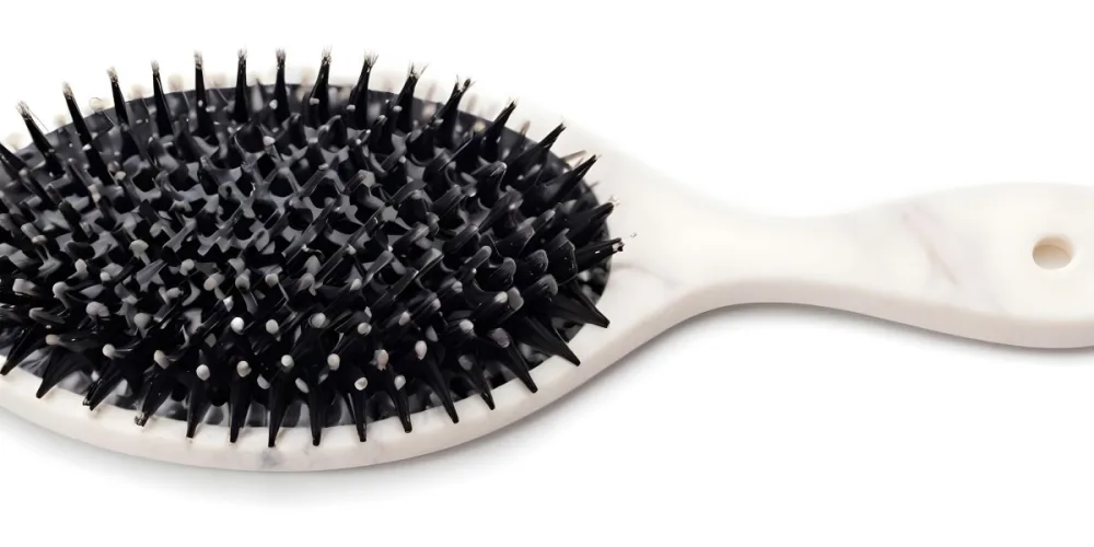 A Black Hair Brush With White Bristles Placed On A Marble Countertop 3
