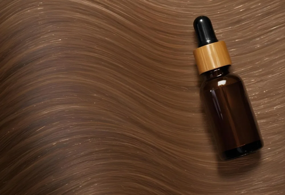 A Brown Glass Bottle With A Dropper On A Background Of Brown Hair The Hair Is Wavy And Shiny The Bottle Is In The Upper Right Corner 9 Ec70