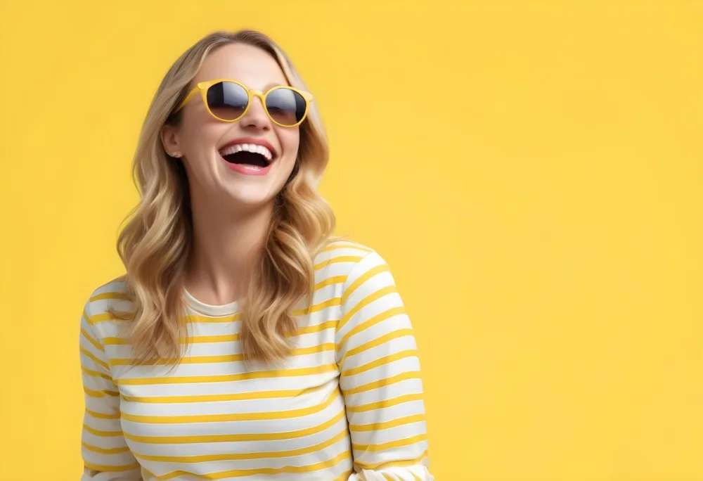 A Caucasian Woman 28 Years Old Blonde Wavy Hair Yellow Sunglasses And A Striped Shirt Laughing In A Yellow Background 9 F621