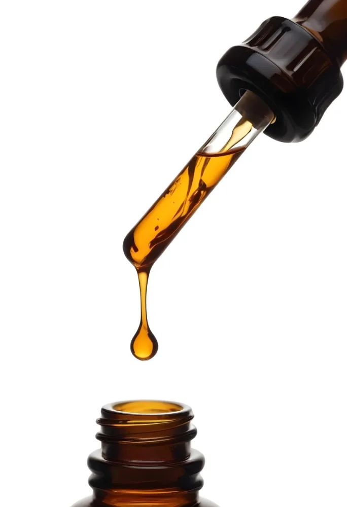 A Close Up Of A Dropper Filled With Amber Liquid Poised Above A Brown Glass Bottle Against A Stark White Background 22 3b89