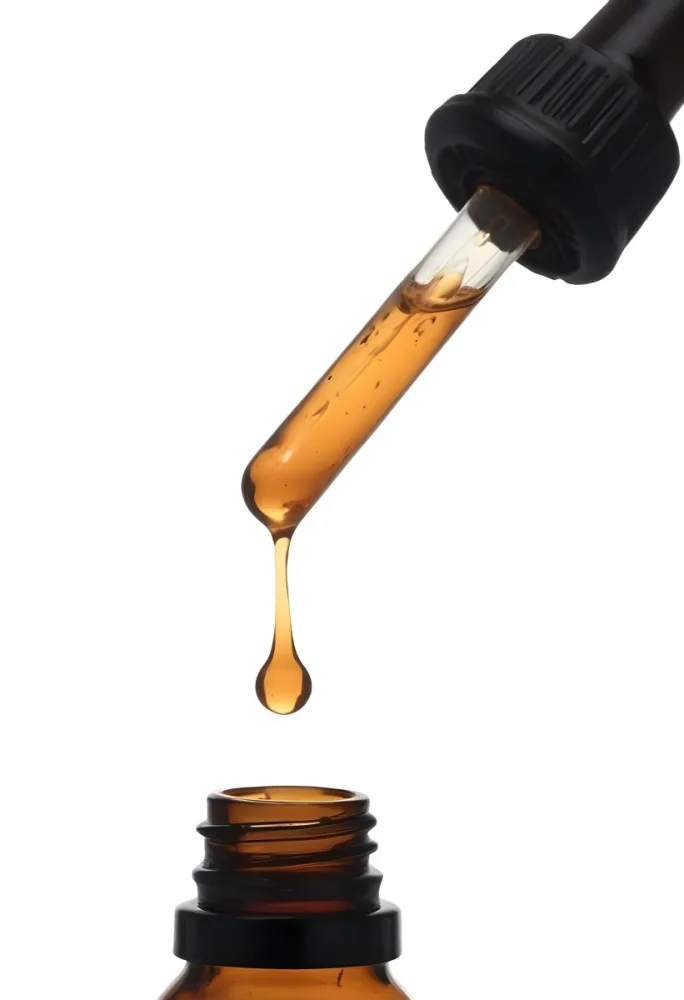 A Close Up Of A Dropper Filled With Amber Liquid Poised Above A Brown Glass Bottle Against A Stark White Background 24 76af