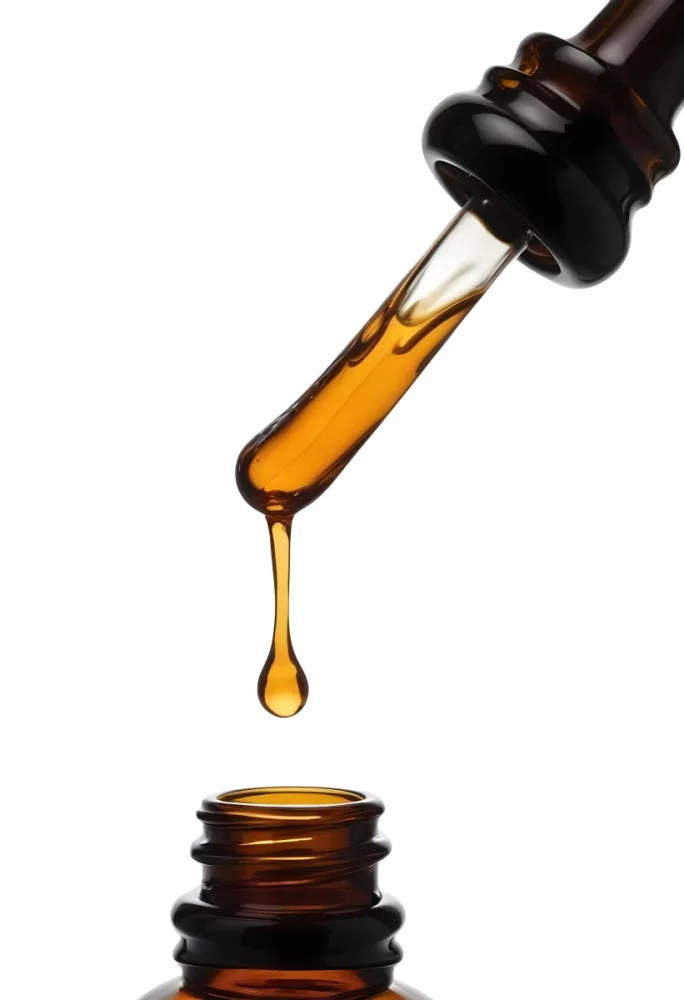 A Close Up Of A Dropper Filled With Amber Liquid Poised Above A Brown Glass Bottle Against A Stark White Background 28 F3d3