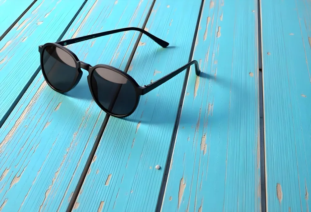 A Pair Of Dark Sunglasses On A Blue Wooden Surface The Wood Has A Distressed Look With Light Brown Undertones 30 7a24