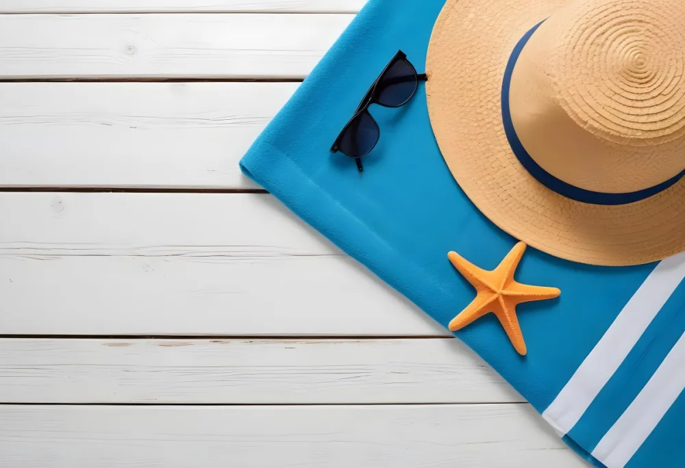 A Straw Hat Sunglasses And A Starfish On A Blue Towel All On A White Wooden Surface Creating A Beach Themed Composition 30 0e42