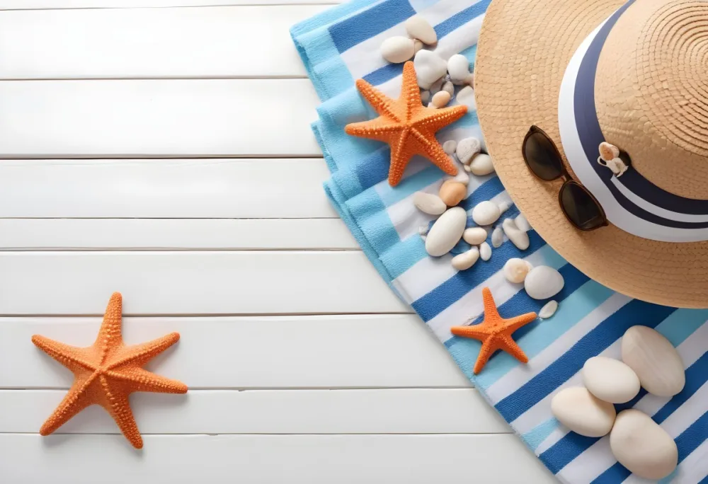 A Straw Hat With A Seashell On Top Of A Striped Towel Sunglasses Sunscreen Starfish And Pebbles On A White Wooden Surface 7 1d92