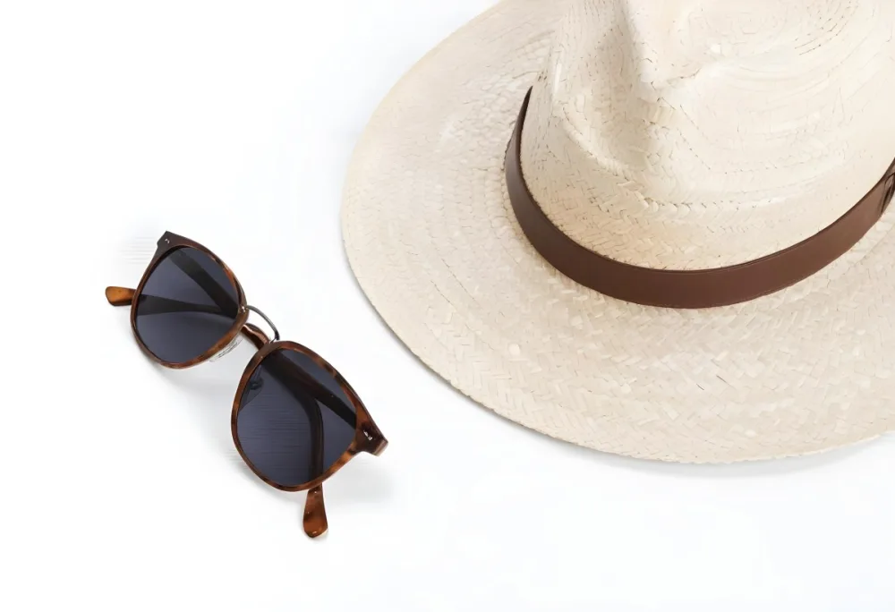A Straw Hat With A White Leather Band And A Pair Of Sunglasses On A White Surface 3 6d26