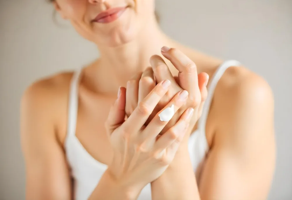 A White Woman 25 Years Old With Fair Skin And Brown Hair Applying Cream On Her Hands In A Bright Room 11 36a6