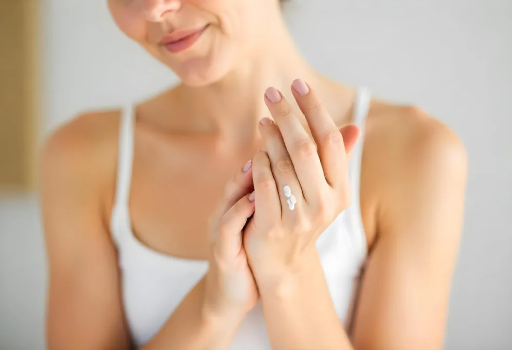 A White Woman 25 Years Old With Fair Skin And Brown Hair Applying Cream On Her Hands In A Bright Room 3 A476
