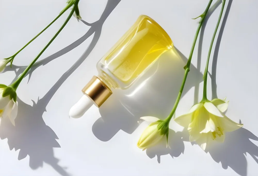 A Yellow Serum In A Glass Bottle With A White Dropper Next To Some White Flowers On A White Background 22 97e0