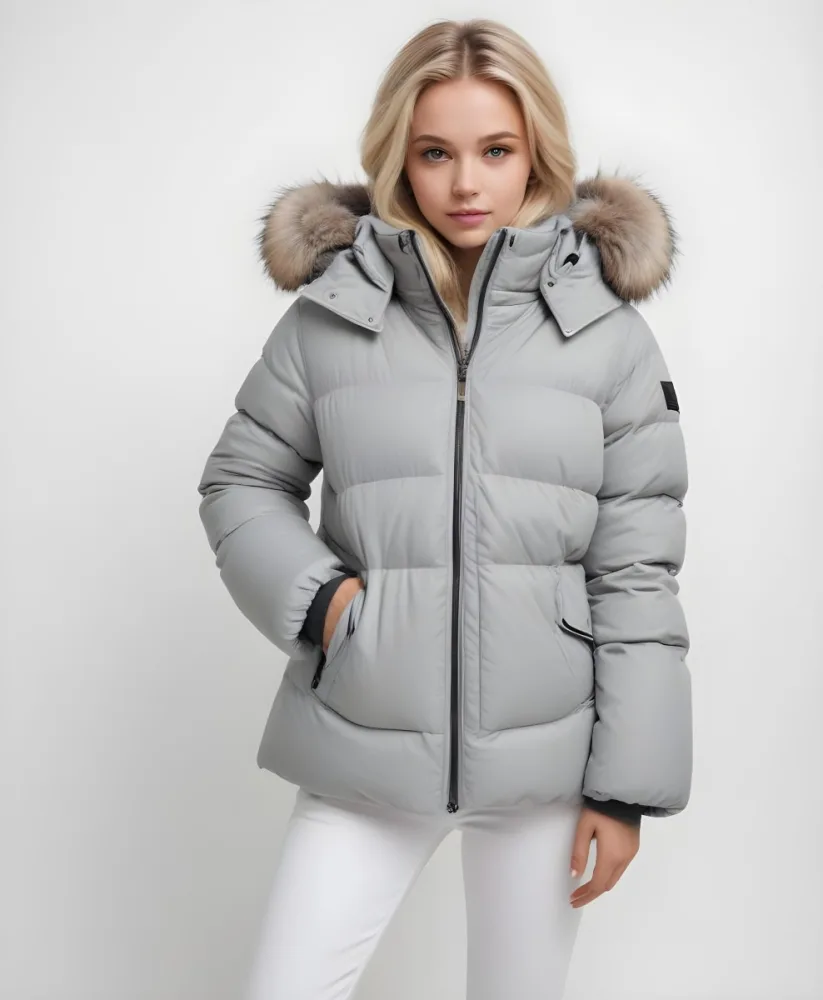 A Young Blonde Woman Wearing A Gray Puffer Jacket With A Large Fur Trimmed Hood Standing Against A White Background 11 D22b