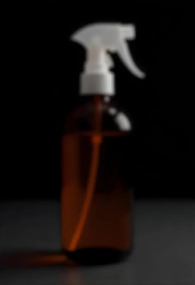 An Amber Glass Spray Bottle With A White Spray Nozzle The Bottle Is Empty The Background Is Black 9 49f0