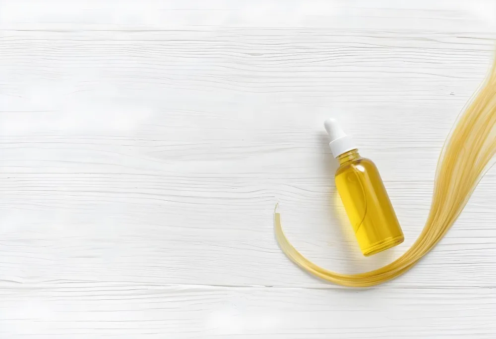 Bottle Of Yellow Hair Oil With A White Cap And A Strand Of Blonde Hair On A White Wooden Table 12 5cb2
