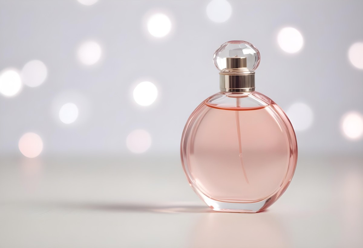 Round Perfume Bottle With A Transparent Cap Filled With A Light Pink Liquid On A White Surface With A Bokeh Background 22 0ef9