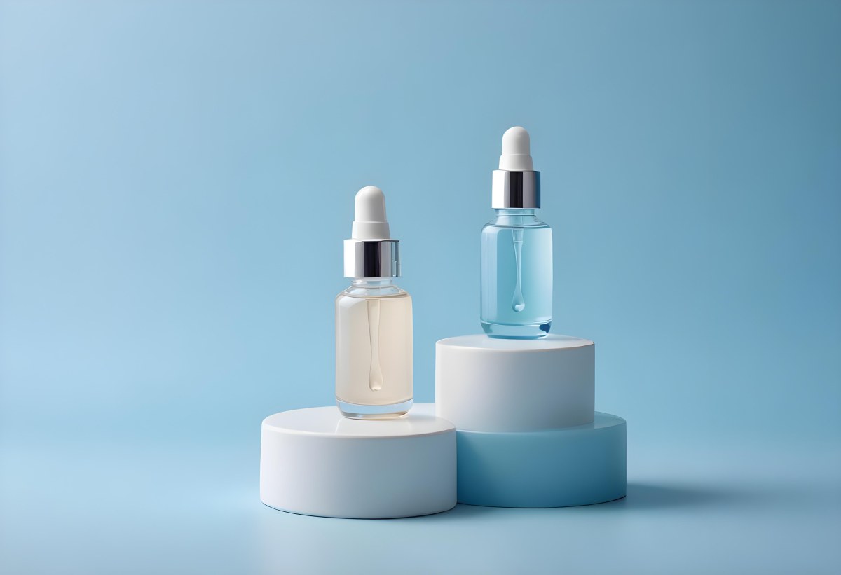 Two Cosmetic Bottles With Droppers One With A Blue Liquid And The Other Transparent On Top Of White Platforms With A Light Blue Background 37 Aa72