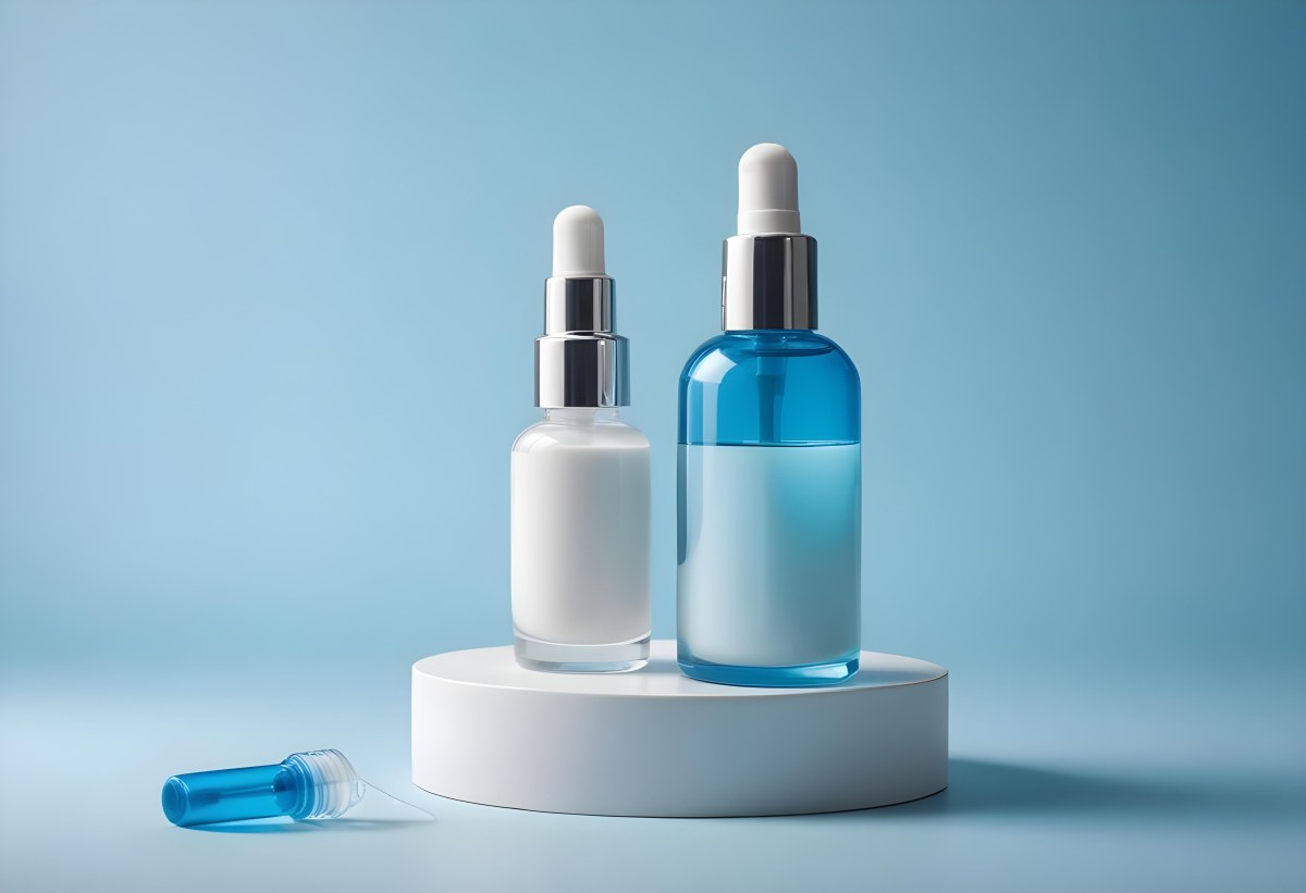 Two Cosmetic Bottles With Droppers One With A Blue Liquid And The Other Transparent On Top Of White Platforms With A Light Blue Background 6 5a9e