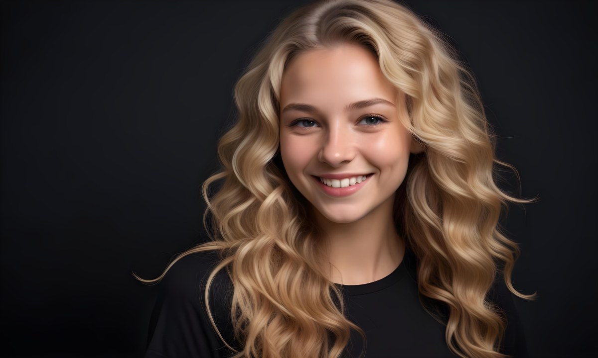Young Caucasian Woman With Long Wavy Blonde Hair And Dark Skin Smiling Softly She Is Wearing A Black Top And Is Positioned Against A Dark Background 81 9931
