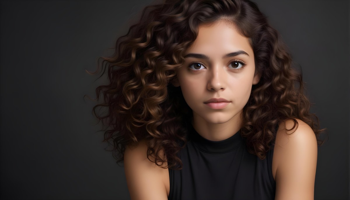 Young Woman With Medium Skin Tone And Long Curly Brown Hair Wearing A Black Sleeveless Top Looking Directly At The Camera With A Neutral Expression The Background Is Dark And Simple Emphasizing Her Features 45 F3ef