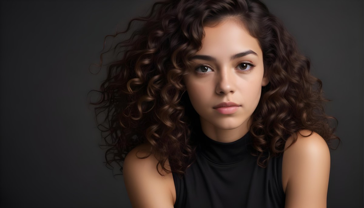Young Woman With Medium Skin Tone And Long Curly Brown Hair Wearing A Black Sleeveless Top Looking Directly At The Camera With A Neutral Expression The Background Is Dark And Simple Emphasizing Her Features 60 Eb95