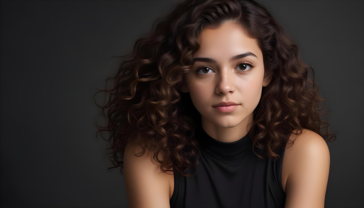 Young Woman With Medium Skin Tone And Long Curly Brown Hair Wearing A Black Sleeveless Top Looking Directly At The Camera With A Neutral Expression The Background Is Dark And Simple Emphasizing Her Features 62 F8c2