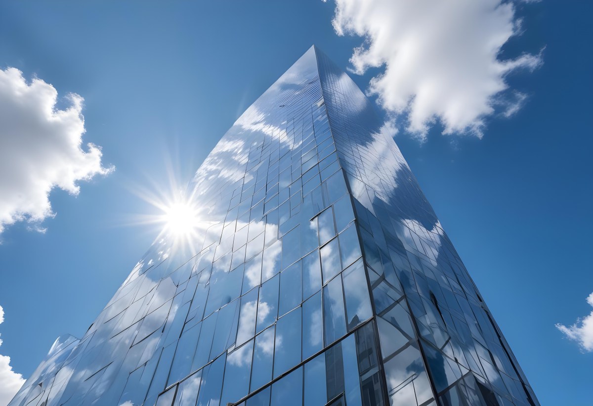 Low Angle Shot Of A Modern Glass Skyscraper Reflecting The Blue Sky And White Clouds Sun Shining Through The Clouds Creating A Bright And Airy Atmosphere 26 9976