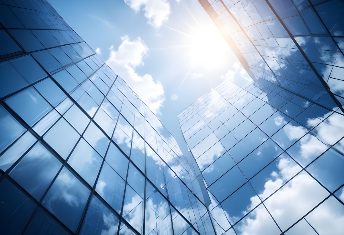 Low Angle Shot Of A Modern Glass Skyscraper Reflecting The Blue Sky And White Clouds Sun Shining Through The Clouds Creating A Bright And Airy Atmosphere 4 5071