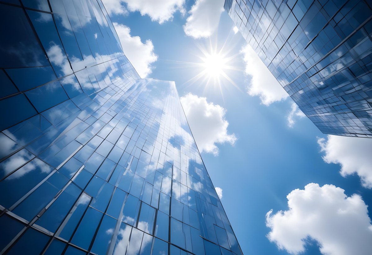 Low Angle Shot Of A Modern Glass Skyscraper Reflecting The Blue Sky And White Clouds Sun Shining Through The Clouds Creating A Bright And Airy Atmosphere 56 C662