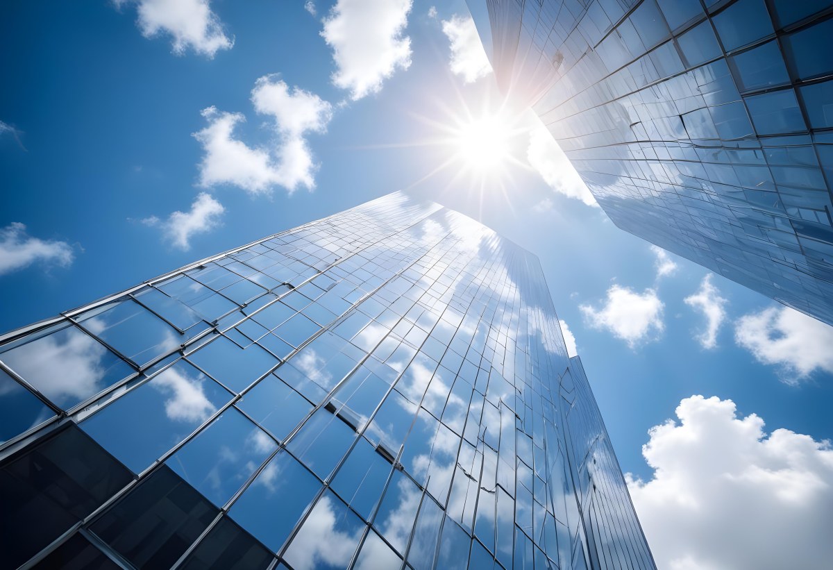 Low Angle Shot Of A Modern Glass Skyscraper Reflecting The Blue Sky And White Clouds Sun Shining Through The Clouds Creating A Bright And Airy Atmosphere 58 Ce09