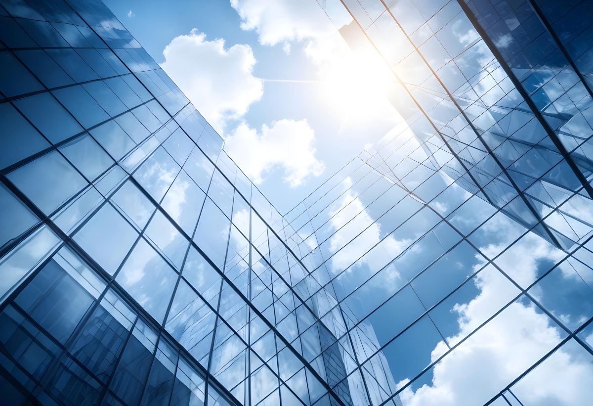 Low Angle Shot Of A Modern Glass Skyscraper Reflecting The Blue Sky And White Clouds Sun Shining Through The Clouds Creating A Bright And Airy Atmosphere 75 4676