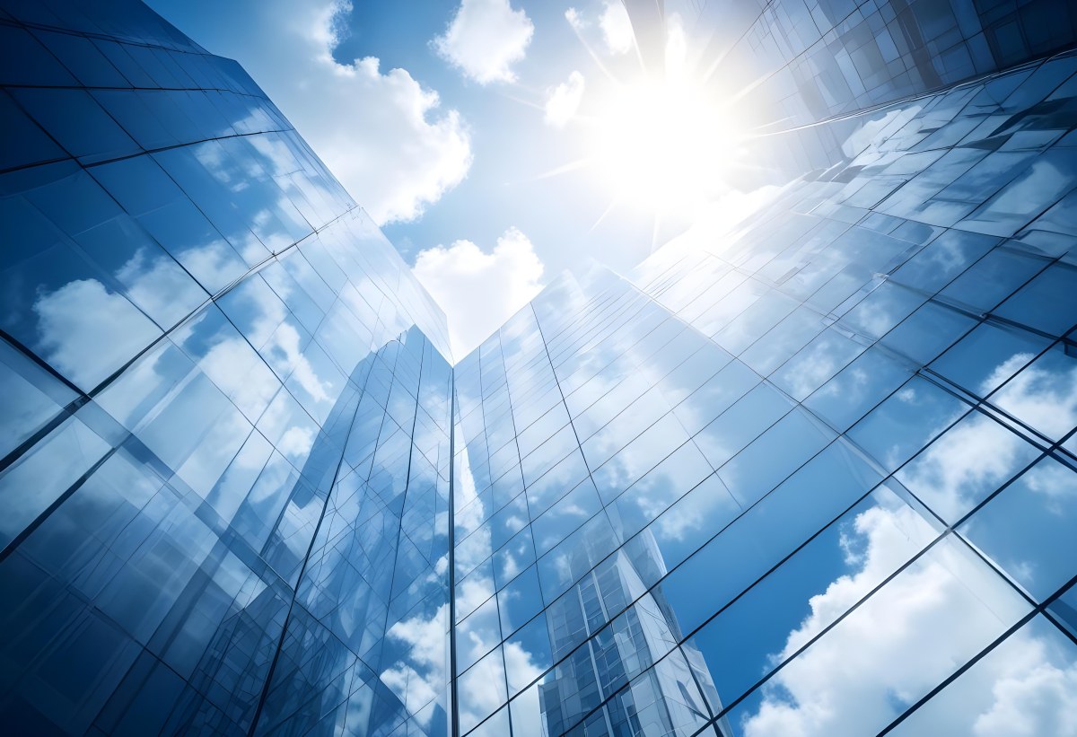 Low Angle Shot Of A Modern Glass Skyscraper Reflecting The Blue Sky And White Clouds Sun Shining Through The Clouds Creating A Bright And Airy Atmosphere 78 F9f8