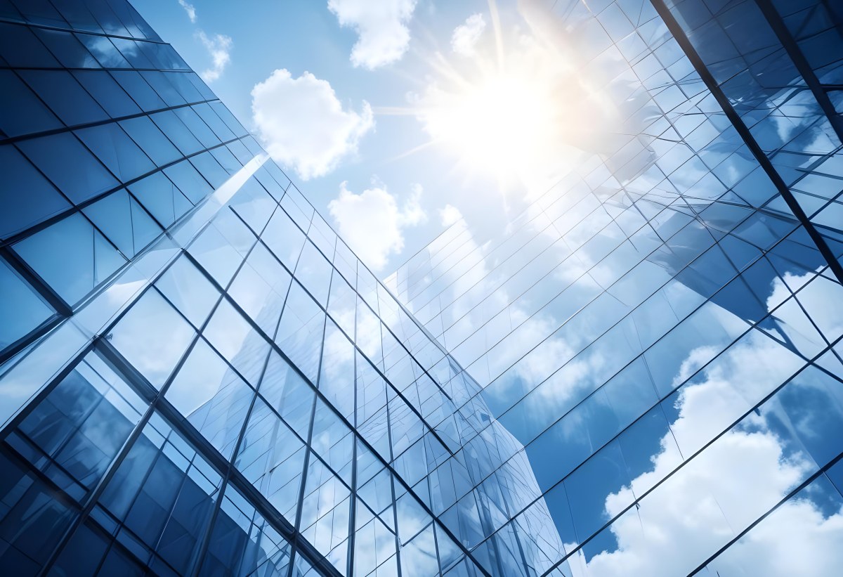 Low Angle Shot Of A Modern Glass Skyscraper Reflecting The Blue Sky And White Clouds Sun Shining Through The Clouds Creating A Bright And Airy Atmosphere 79 5866