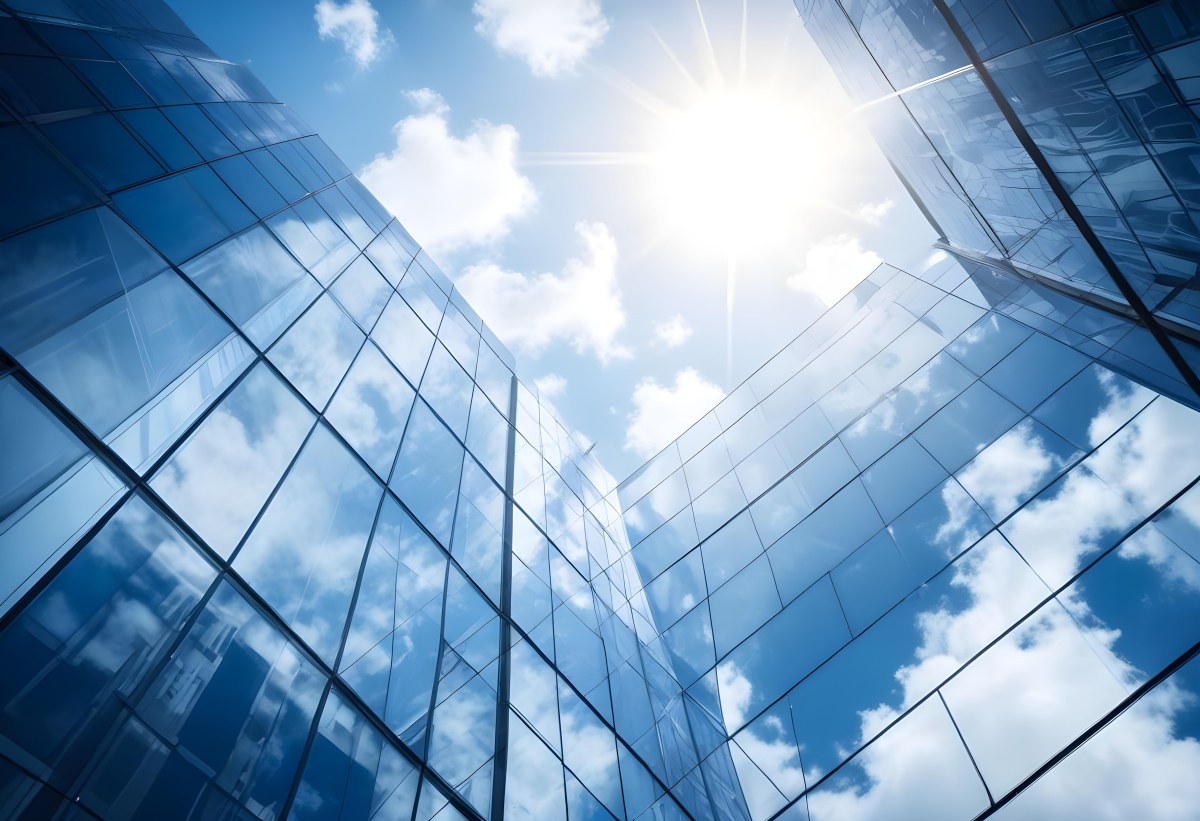 Low Angle Shot Of A Modern Glass Skyscraper Reflecting The Blue Sky And White Clouds Sun Shining Through The Clouds Creating A Bright And Airy Atmosphere 80 658e