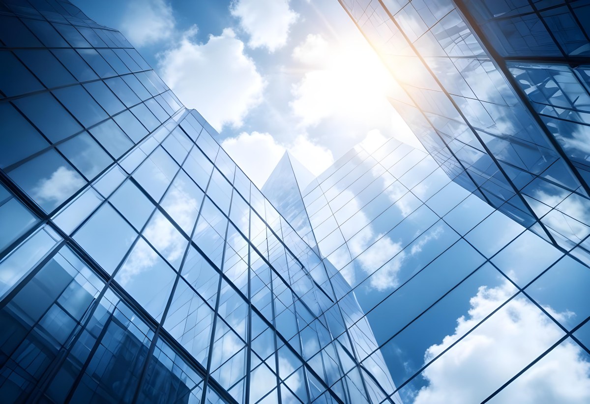 Low Angle Shot Of A Modern Glass Skyscraper Reflecting The Blue Sky And White Clouds Sun Shining Through The Clouds Creating A Bright And Airy Atmosphere 82 2635
